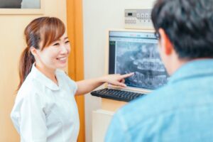 歯科衛生士さんが歯のレントゲンを患者さんに説明している写真