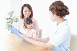 歯科スタッフから子どもの歯の健康についての説明を受ける親子の写真