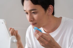 鏡の前でフロスを30～40cm出してる男性の写真